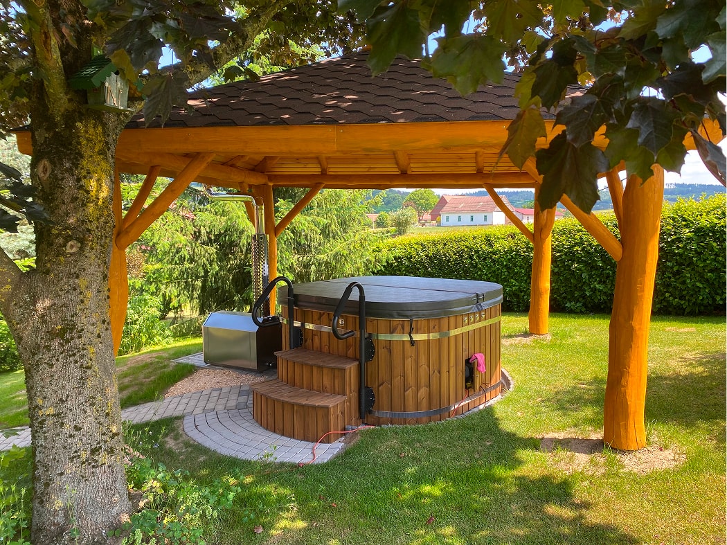 Gardenvity wood fired Square hot tub under wooden pergola in green garden setting