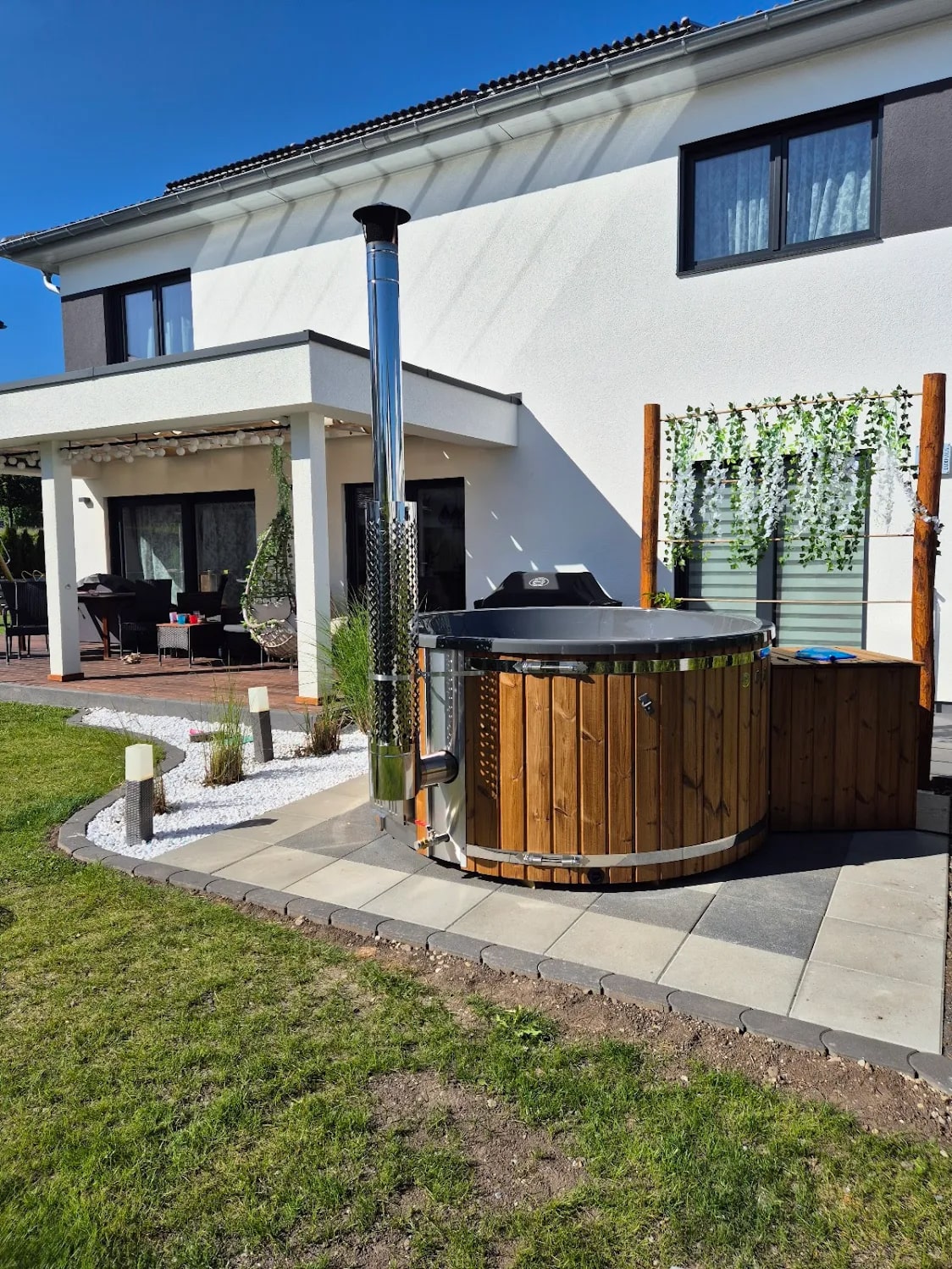 Gardenvity wood fired hot tub beside a modern house in a landscaped backyard